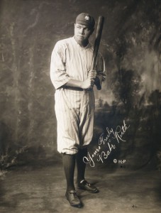Babe Ruth, full-length portrait, standing, facing slightly right, in baseball uniform, holding baseball bat. Facsimile signature on image: "Yours truly "Babe" Ruth." Via Wikipedia