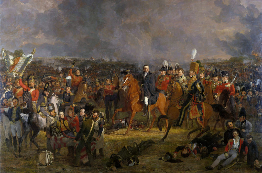Jan Willem Pieneman: The Battle of Waterloo (1824). Duke of Wellington, centre, flanked on his left by Lord Uxbridge in hussar uniform. On the image's far left, Cpl. Styles of the Royal Dragoons flourishes the eagle of the 105eme Ligne. The wounded Prince of Orange is carried from the field in the foreground. Via Wikipedia.